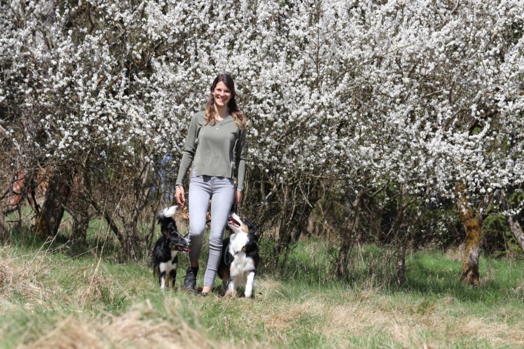 Aylin Wiesner beim entspannten Spaziergang mit ihren beiden Hunden vor blühenden Bäumen