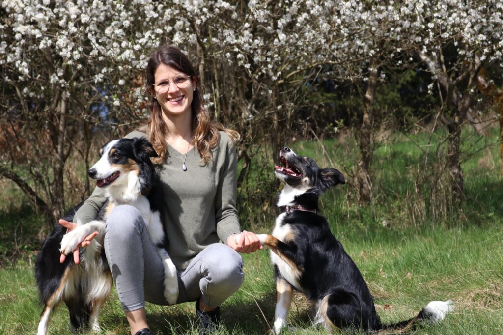 Hund gibt Aylin Wiesner vertrauensvoll die Pfote beim Training auf der Wiese